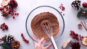 A hand holding a bowl with dry chocolate flour mixture.