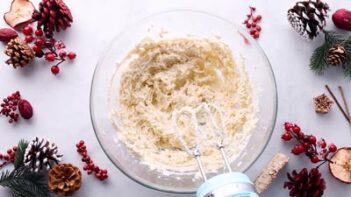 An electric mixer over a bowl with creamed butter.