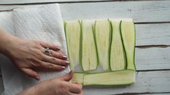 blotting zucchini slices with a paper towel