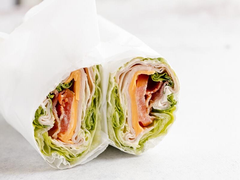 Two upright lettuce wrap halves with turkey, cheddar, bacon, and tomato