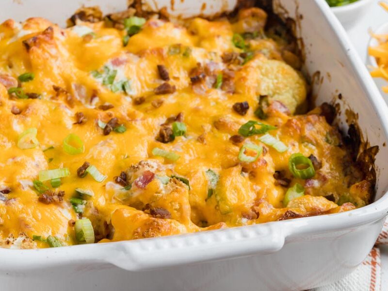 baked casserole with cauliflower topped with cheddar cheese and green onion