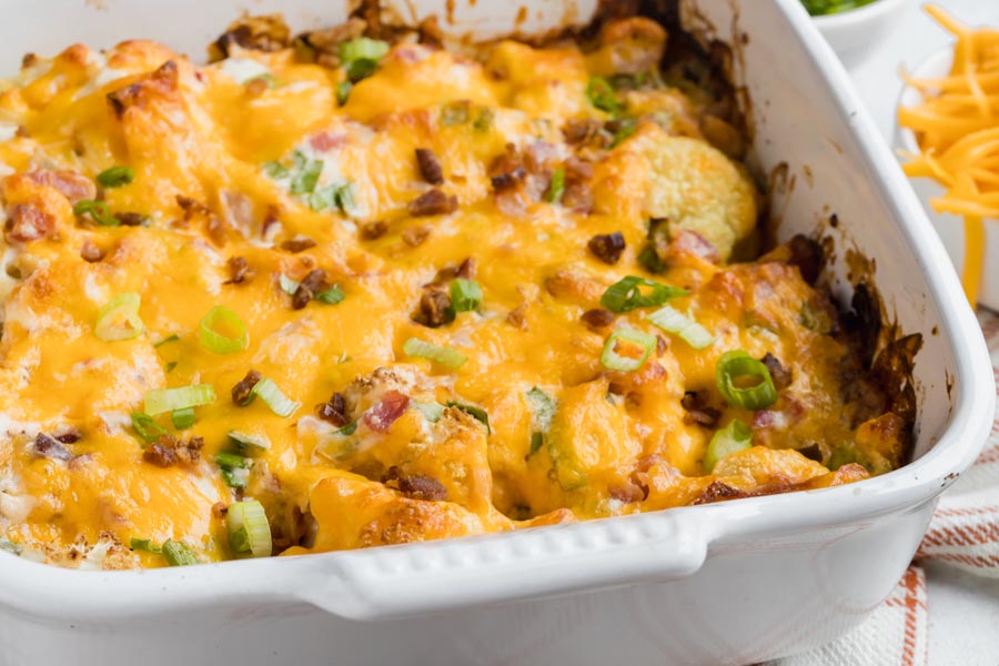 baked casserole with cauliflower topped with cheddar cheese and green onion