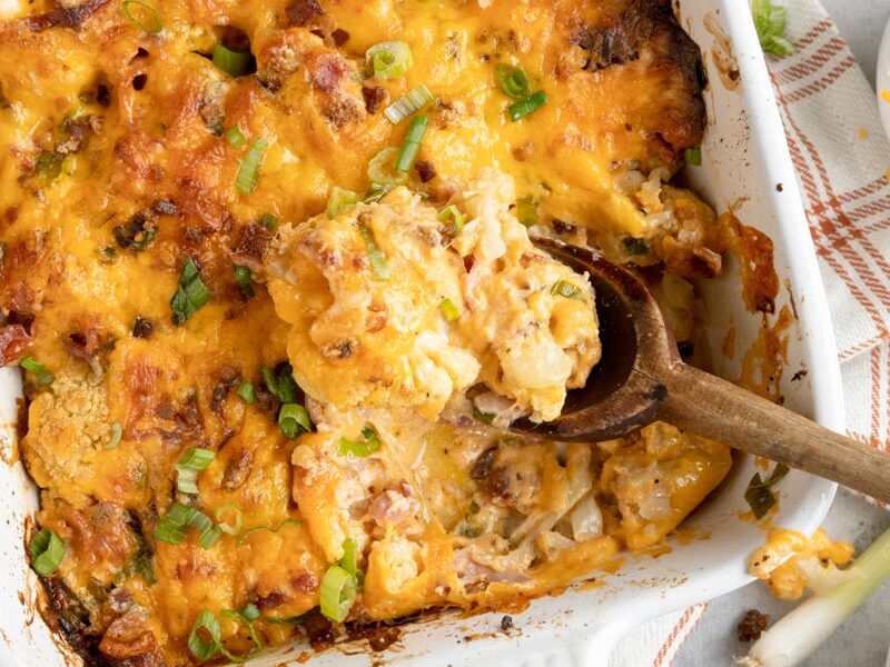 a wooden spoon holding a spoonful of cauliflower casserole