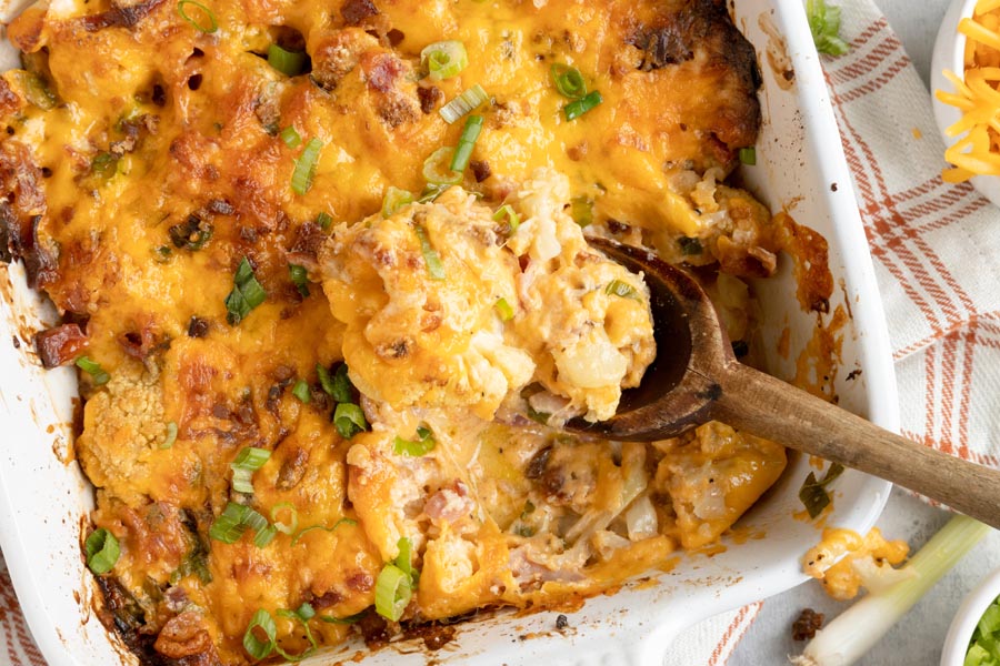 a wooden spoon holding a spoonful of cauliflower casserole