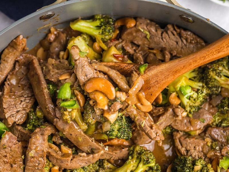 A skillet with cooked steak in a cashew broccoli sauce.