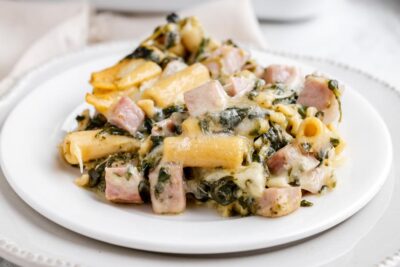 Low-carb ham and Swiss ziti casserole with spinach and melted cheese on a white plate.