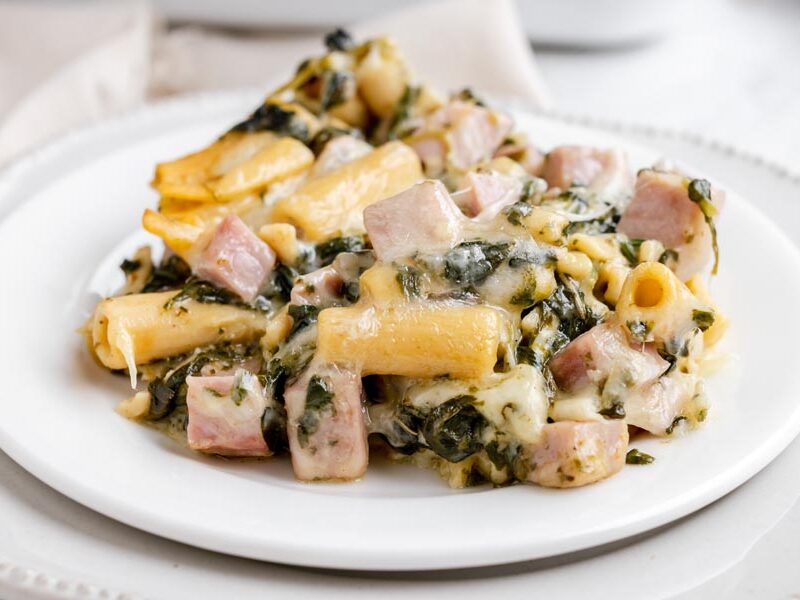 Low-carb ham and Swiss ziti casserole with spinach and melted cheese on a white plate.
