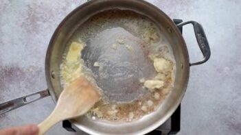 Butter melting in a skillet as garlic begins to sauté.