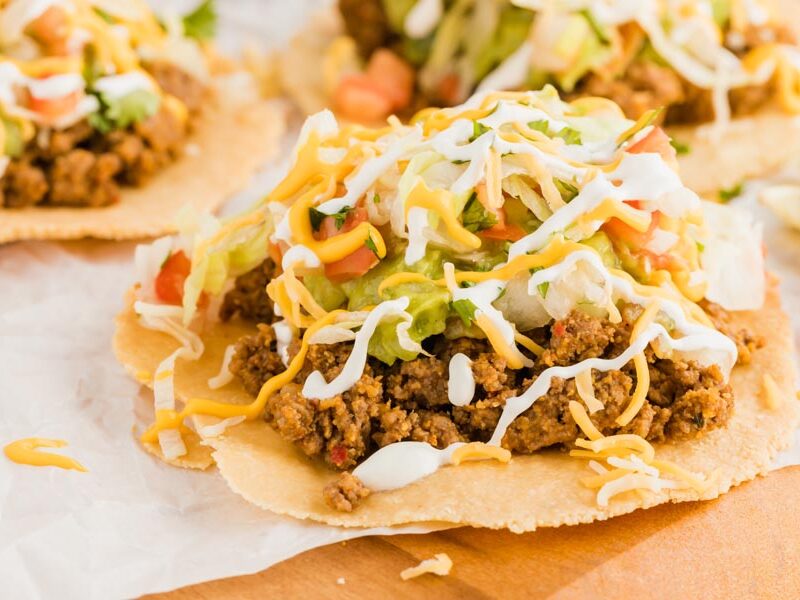 tostada shells with ground beef topped with cheese and pico de gallo