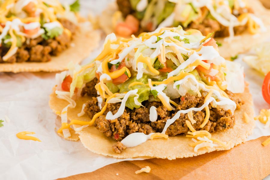 tostada shells with ground beef topped with cheese and pico de gallo