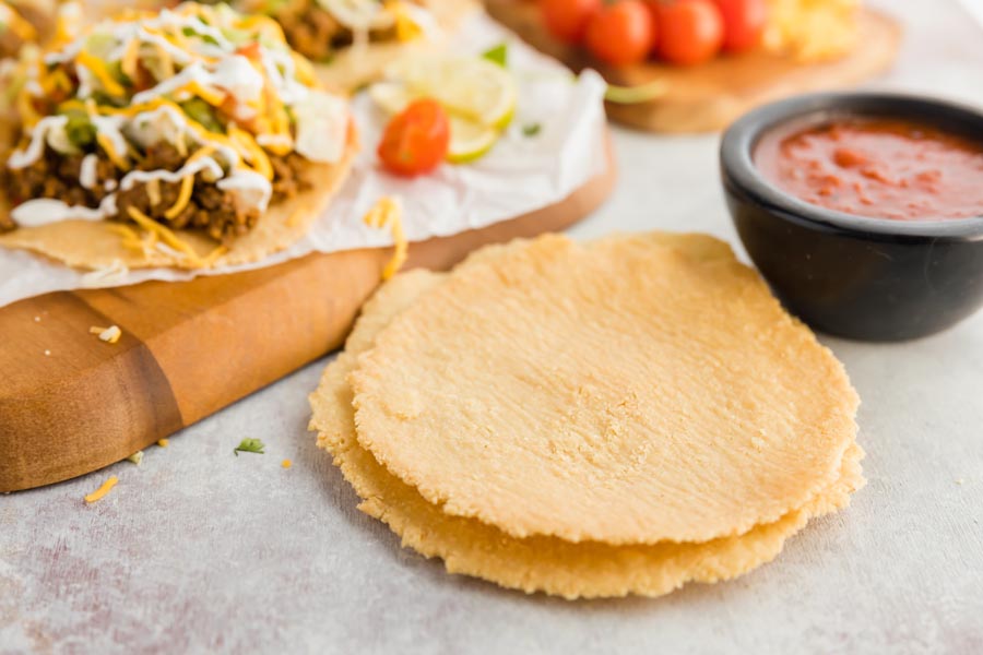 two crispy shells in front of tostadas and salsa