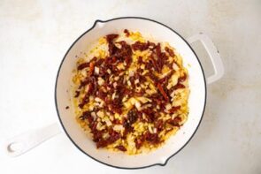 Sauteed sun-dried tomatoes and onions in a skillet.