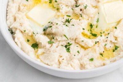 Creamy mashed turnips in a dish topped with melted butter and chopped parsley.