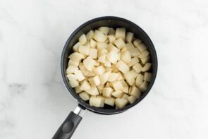 A saucepan with cooked diced turnips inside.
