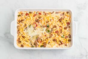 Wet eggs mixed in a casserole with shredded cheese on top.