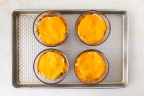 Mexican lasagna bowls after baking, with melted cheese tops, cooling on a baking sheet.
