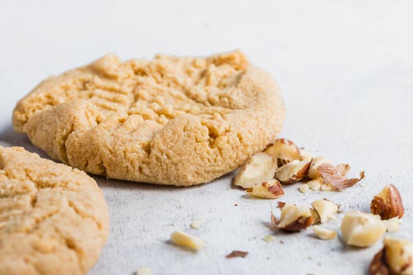 two peanut butter cookies with chopped nuts next to them