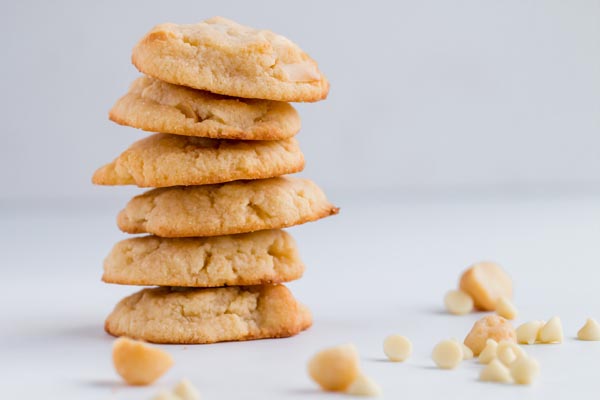a stack of white chocolate macadamia nut cookies with nuts next to it
