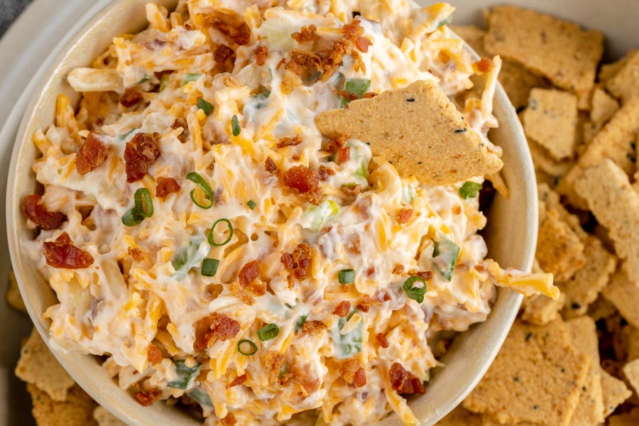 looking down on a bowl with a creamy dip with bacon and cheese surrounded by crackers