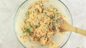 a mixture of cheese and mayo spread in a bowl with a wooden spoon