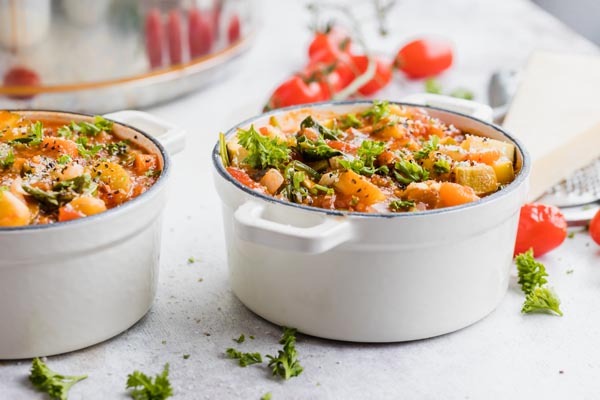 two bowls of minestrone soup in white cast iron bowls