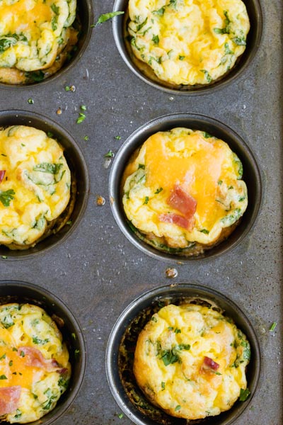a tray with six mini frittatas inside filled with bacon and spinach