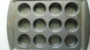 a muffin tray with oil coated in the cavities