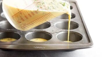 pouring egg mixture into a muffin tin from a pyrex measuring cup