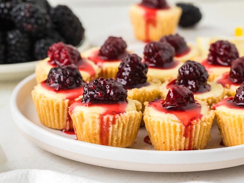 A plate of low-carb mini cheesecakes topped with blackberry syrup.