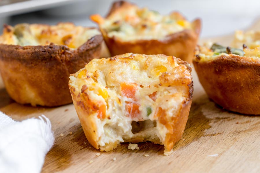 A mini keto chicken pot pie with a bite taken out to reveal the creamy chicken and mixed vegetable filling inside.
