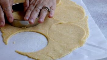 Four-inch circles being cut from the rolled keto pot pie dough with a round biscuit cutter.