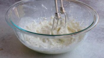 Softened cream cheese and heavy cream being mixed together until smooth for the creamy chicken pot pie filling.