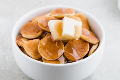 mini pancake cereal with butter and sugar free syrup on top in a small bowl