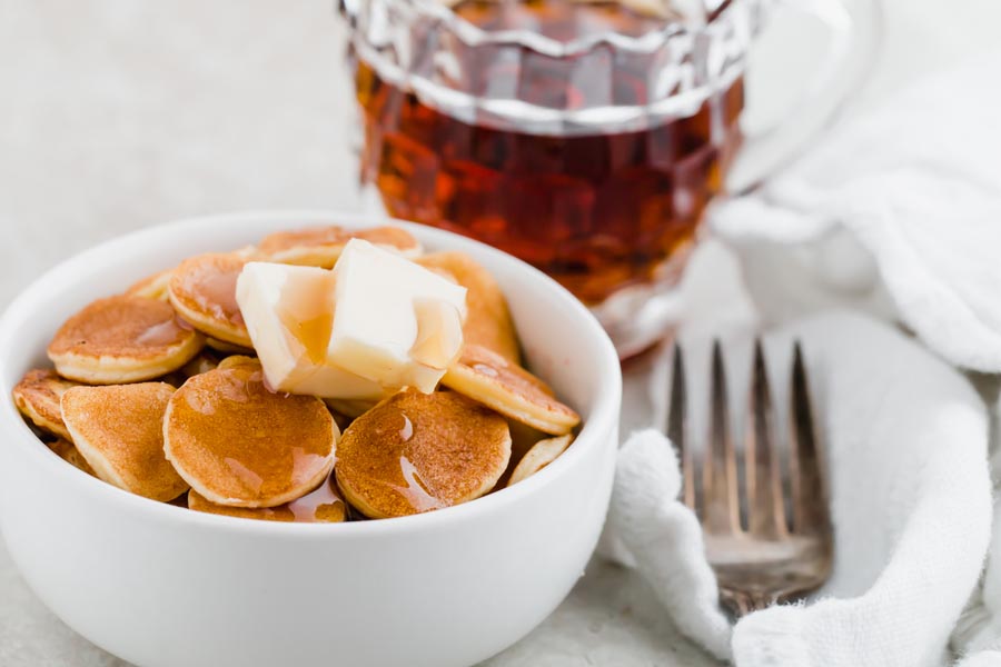 a small bowl of tiny keto pancakes with maple syrup