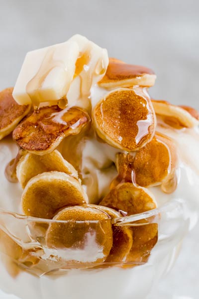 mini pancakes over ice cream topped with butter and syrup dripping down