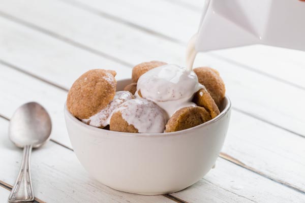 pouring cold milk over a bowl filled with little snickerdoodle cookies