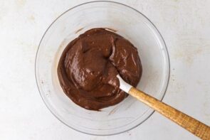 Thick, glossy chocolate batter mixed in a bowl with a rubber spatula.
