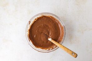 Chocolate batter with a smoother consistency being stirred with a spatula in a glass bowl.