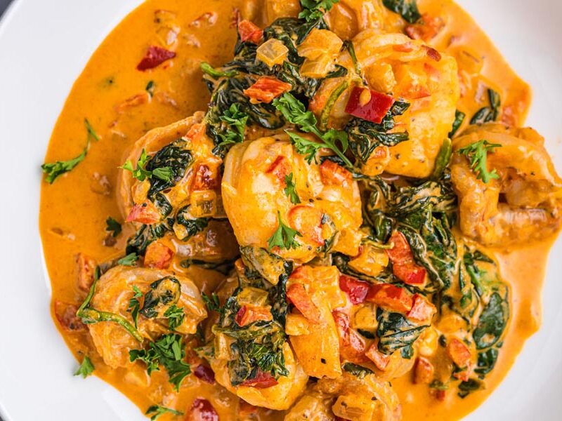A plate of shrimp and spinach in a creamy red sauce.