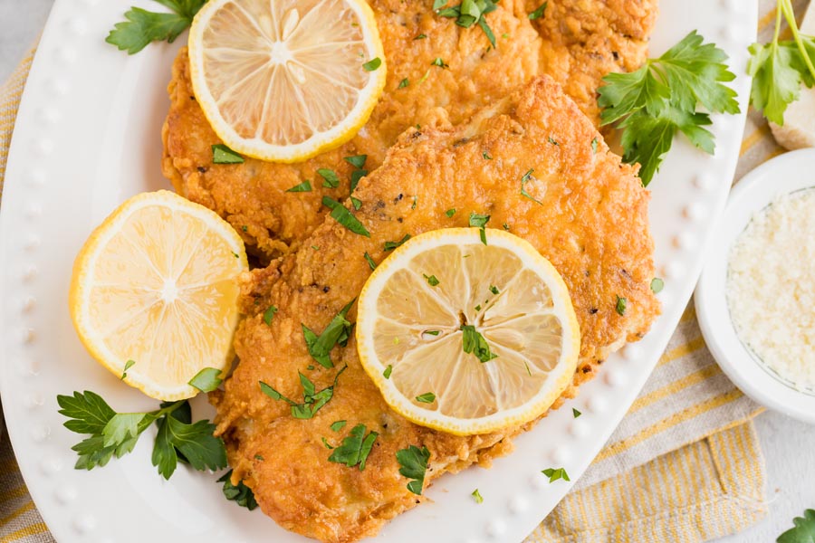 close up of crispy chicken breast on a plate with a lemon slice on top