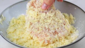coating a chicken breast with shredded cheese