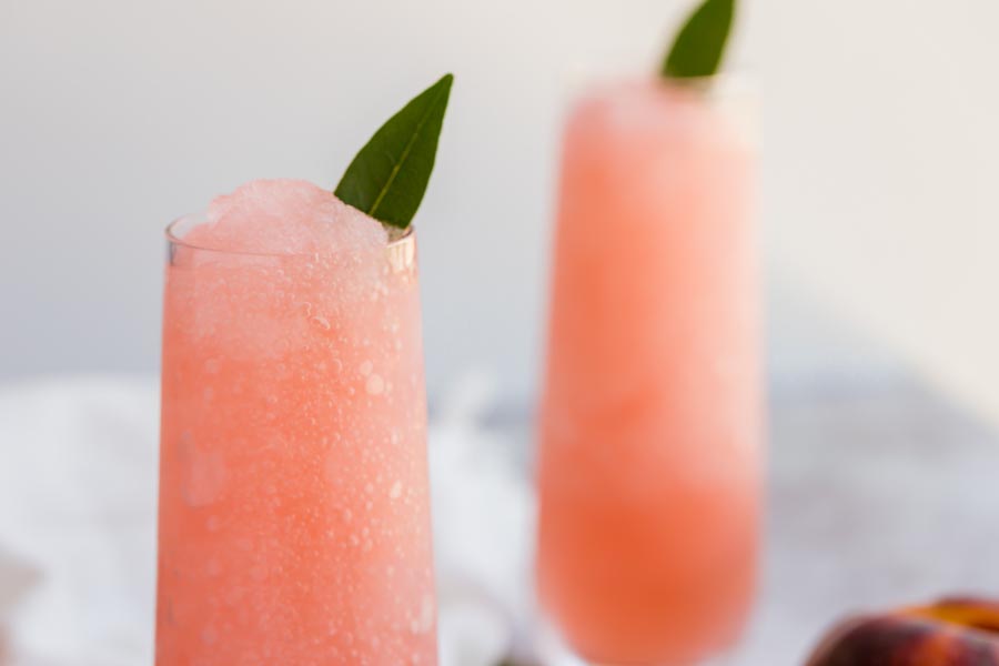 a frosty champagne glass filled with a frozen cocktail and a green leaf as a garnish