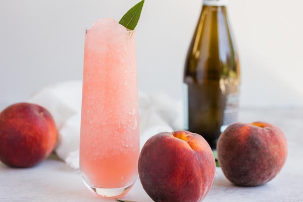 a frozen blended cocktail with a bottle of prosecco in the background