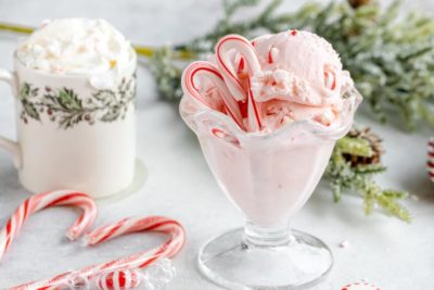 a bowl of peppermint ice cream with candy canes and a hot chocolate in the background