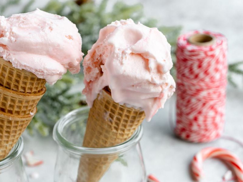 pink ice cream scooped into cones with red thread and a candy cane in the background