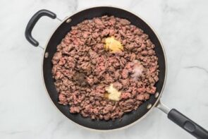 A skillet with cooked ground beef and spices on top.
