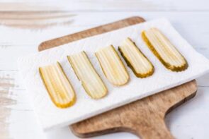 Sliced pickles arranged on a paper towel to drain.