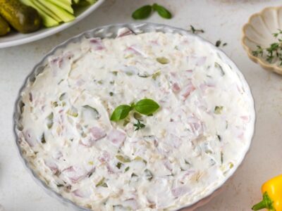 Creamy pickle wrap dip made with chopped dill pickles and ham, garnished with fresh herbs in a serving dish.