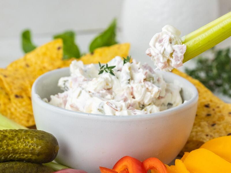 Pickle wrap dip served in a bowl with celery, bell peppers, pickles, and tortilla chips for dipping.