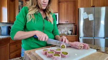 Slicing deli meat-wrapped pickles into bite-sized pieces.